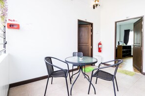 A room with a round glass table, four black chairs, a wooden door, and a key box on the wall. - The Cube Sathorn Boutique (Bangkok)