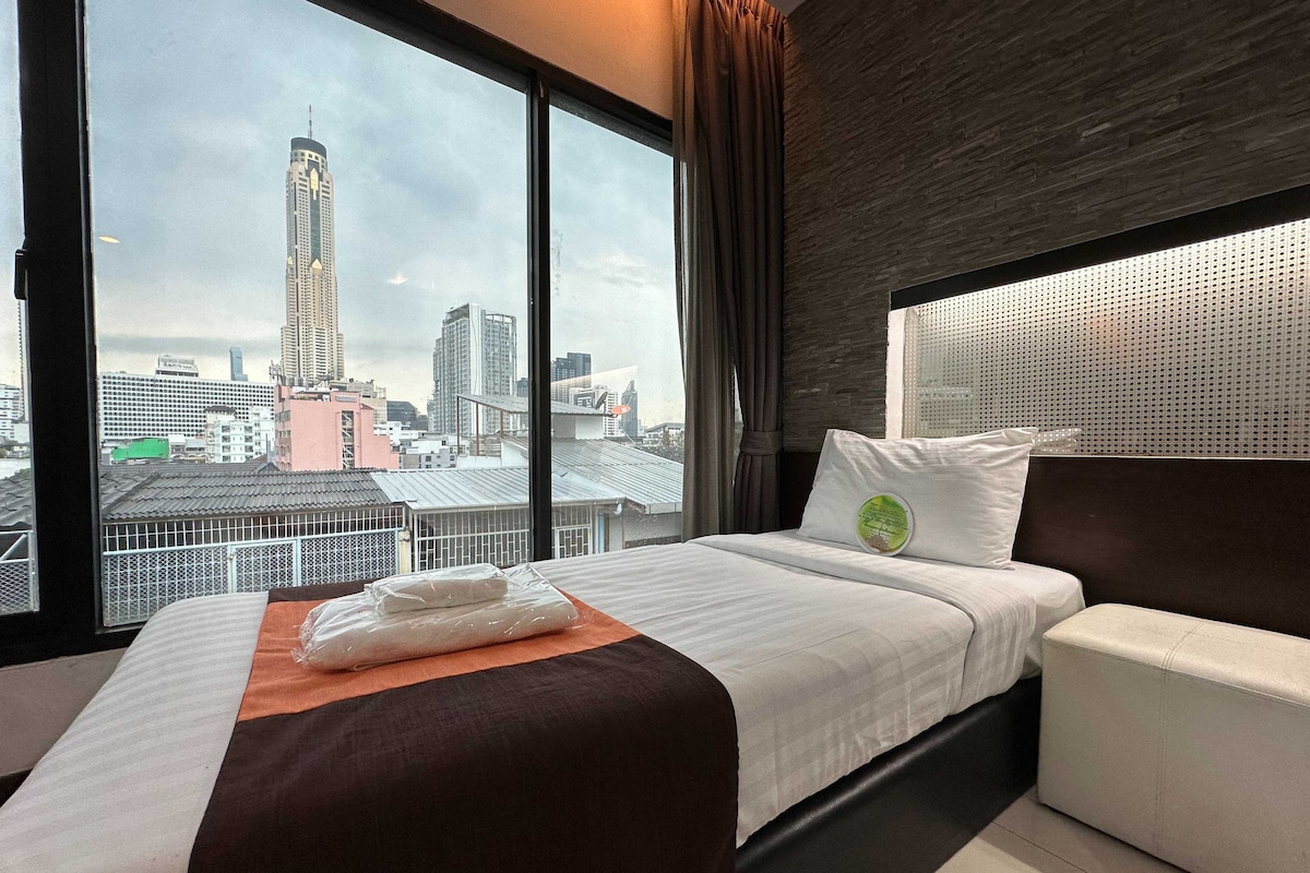Une chambre d’hôtel dotée d’un grand lit, d’un canapé, offrant une vue sur la ville et présentant un design moderne.