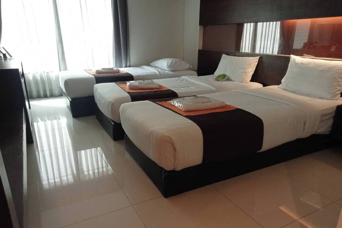 Ein Hotelzimmer mit zwei Betten, einem großen Fenster und modernem Design.