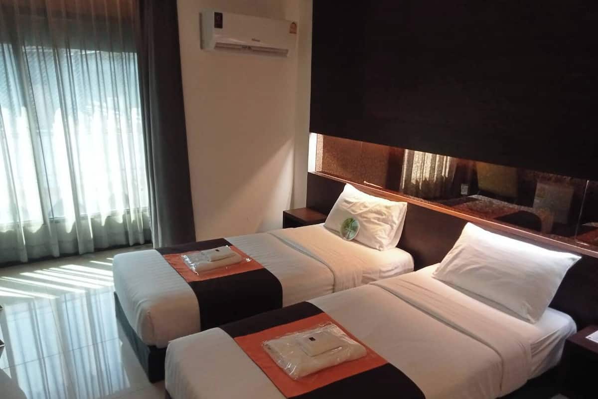 Ein Hotelzimmer mit zwei Betten, einem großen Fenster mit Vorhängen, einer Klimaanlage und einem Nachttisch mit Lampe.