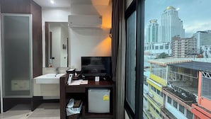 Ein Hotelzimmer mit Schreibtisch, Fernseher und Blick auf die Stadtlandschaft.
