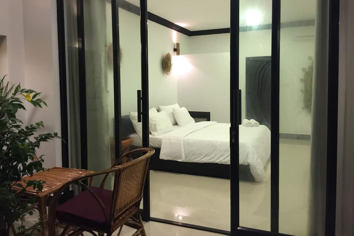Habitación de hotel con cama, una silla, una mesa y una planta en maceta.