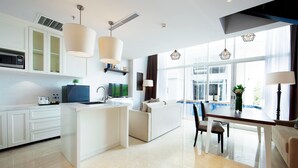 Una cuina moderna amb una illa central, armaris blancs i una zona de menjador amb taula i cadires.