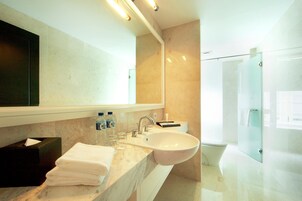A modern bathroom with a large sink, mirror, and glass shower enclosure.