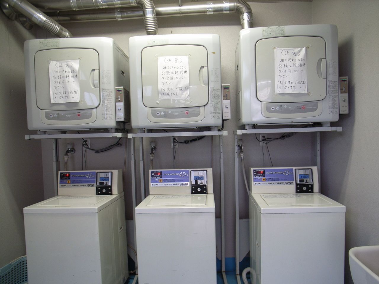 Three washing machines with control panels and notes on them.