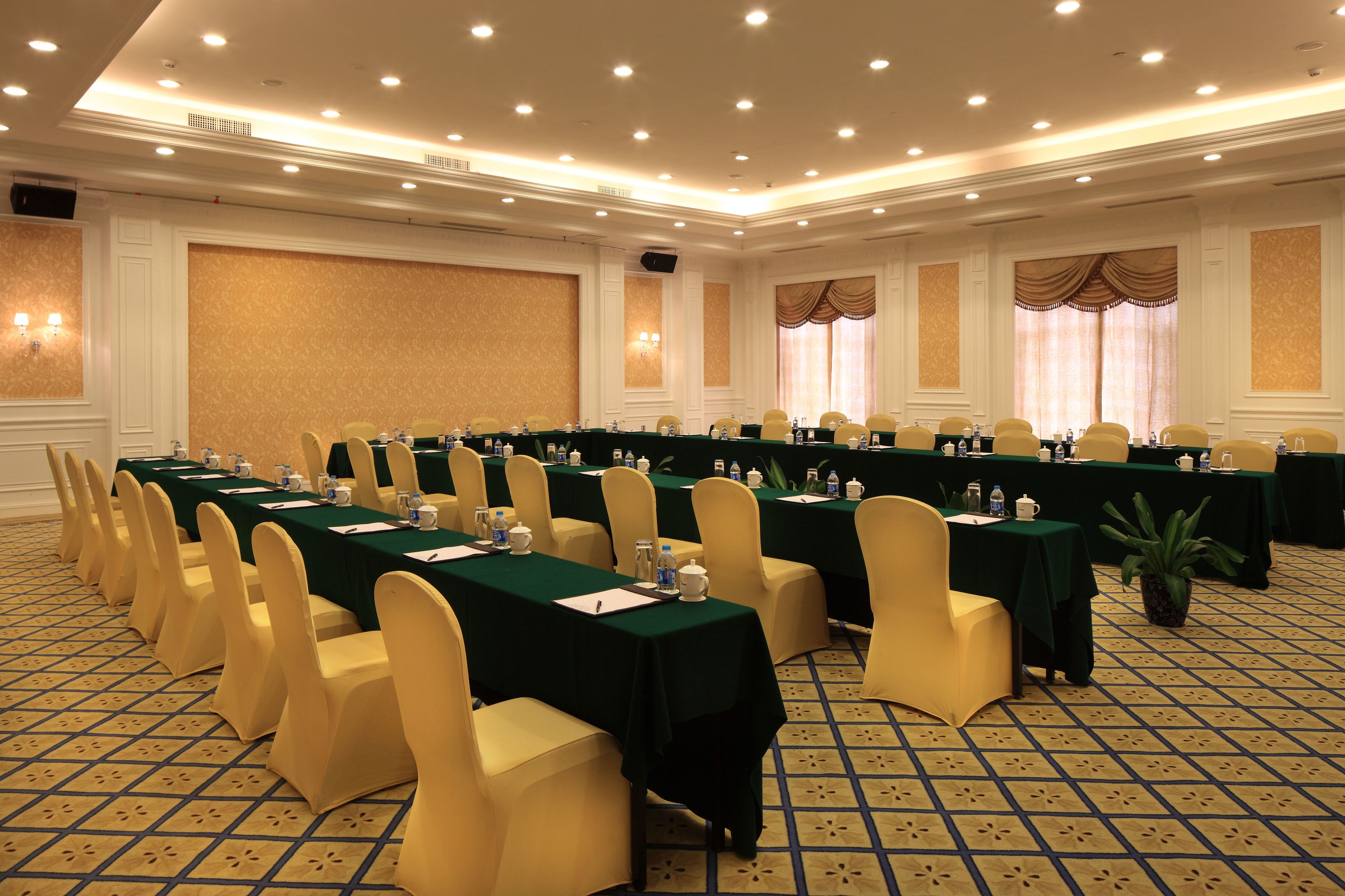 A conference room with long tables, chairs, and a carpeted floor.