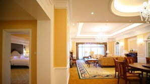 A hotel room with a bed, a sitting area with a sofa and chairs, a dining table, and a chandelier. - Anqing Country Garden Phoenix Hotel (Anqing)