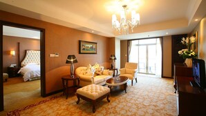 A hotel room with a large bed, a sitting area with a sofa and armchairs, a coffee table, and a television. - Anqing Country Garden Phoenix Hotel (Anqing)
