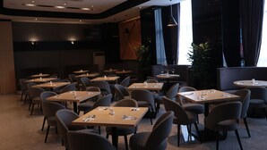 A modern restaurant with multiple tables and chairs, large windows, and a dark interior. - Imperial Riverbank Hotel Kuching (Kuching)