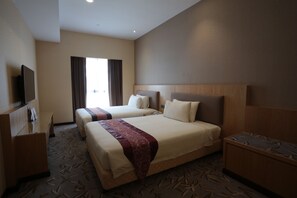 Une chambre d’hôtel avec deux lits, un bureau, une télévision et une fenêtre avec des rideaux.