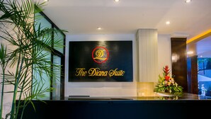 Un comptoir d’accueil avec une pancarte indiquant « La suite Diana » et une plante décorative placée à gauche.