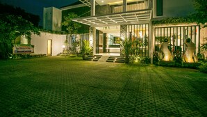 Un bâtiment moderne à deux étages, doté d’une entrée abritée, de plantes en pot et d’une allée pavée.
