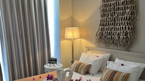 A hotel room with a bed, pillows, a lamp, a wall hanging, and a window with curtains. - Conny's Boutique Hotel - Adults Only (Manavgat)