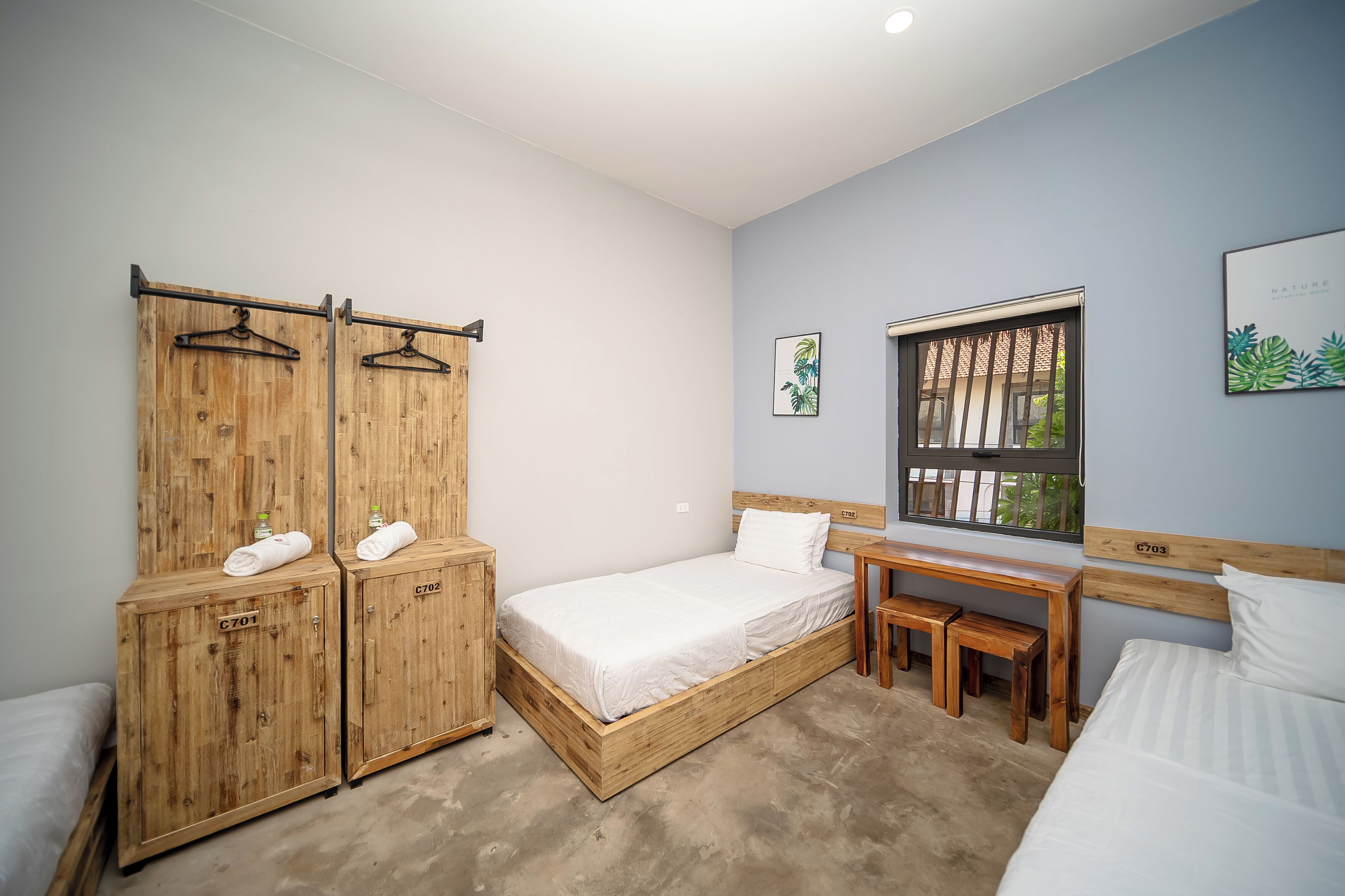Un dormitorio con una cama individual, un armario de madera, un escritorio y una ventana con vistas.