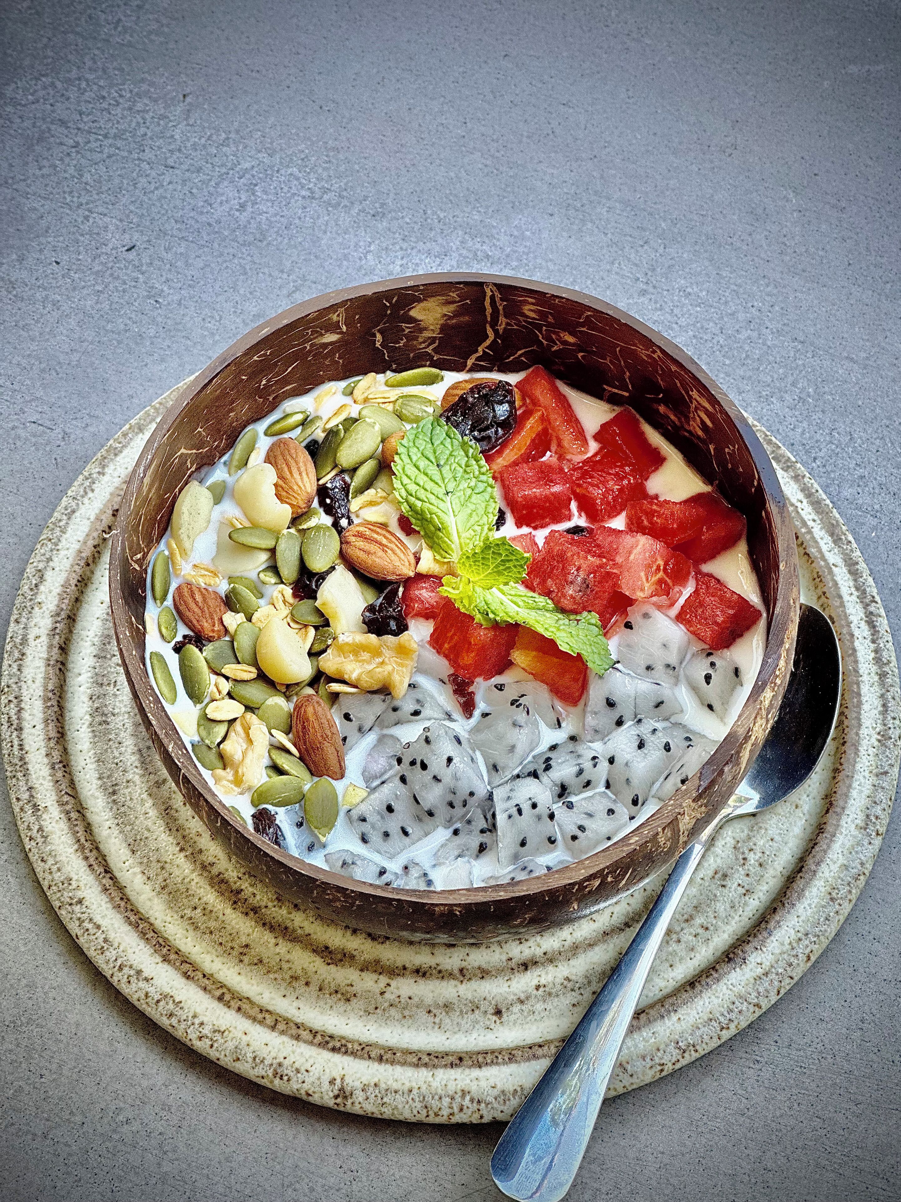 Un bol de postre con diversas frutas y nueces sobre un plato con textura.
