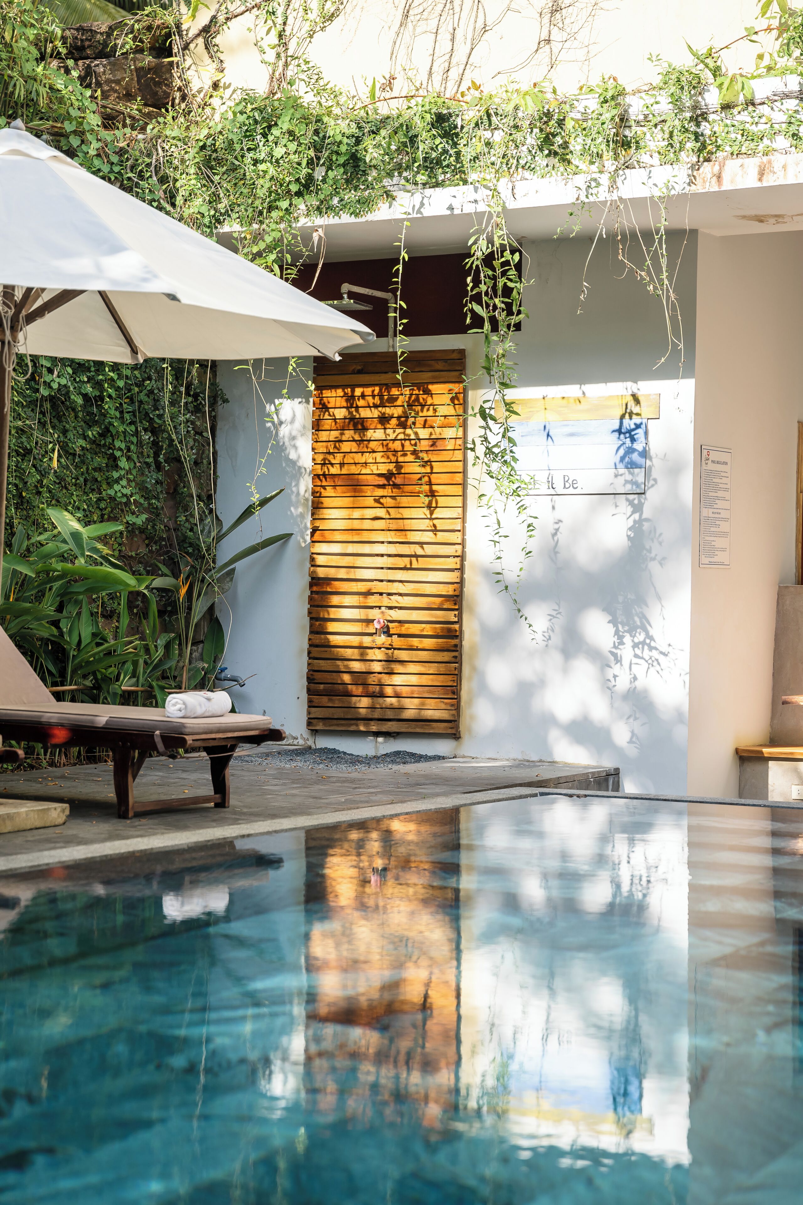 Una piscina al aire libre, sombrillas, sillones reclinables de piscina