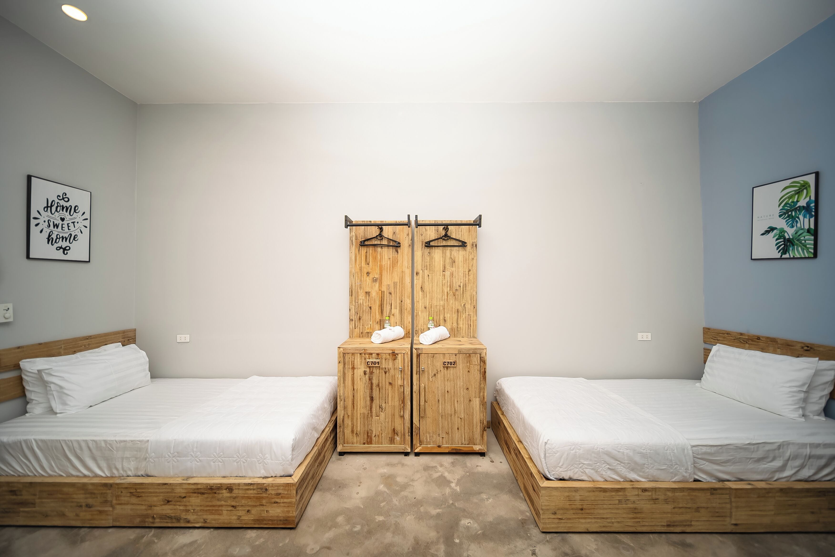 Habitación con dos camas individuales, armario de madera y pared azul claro.
