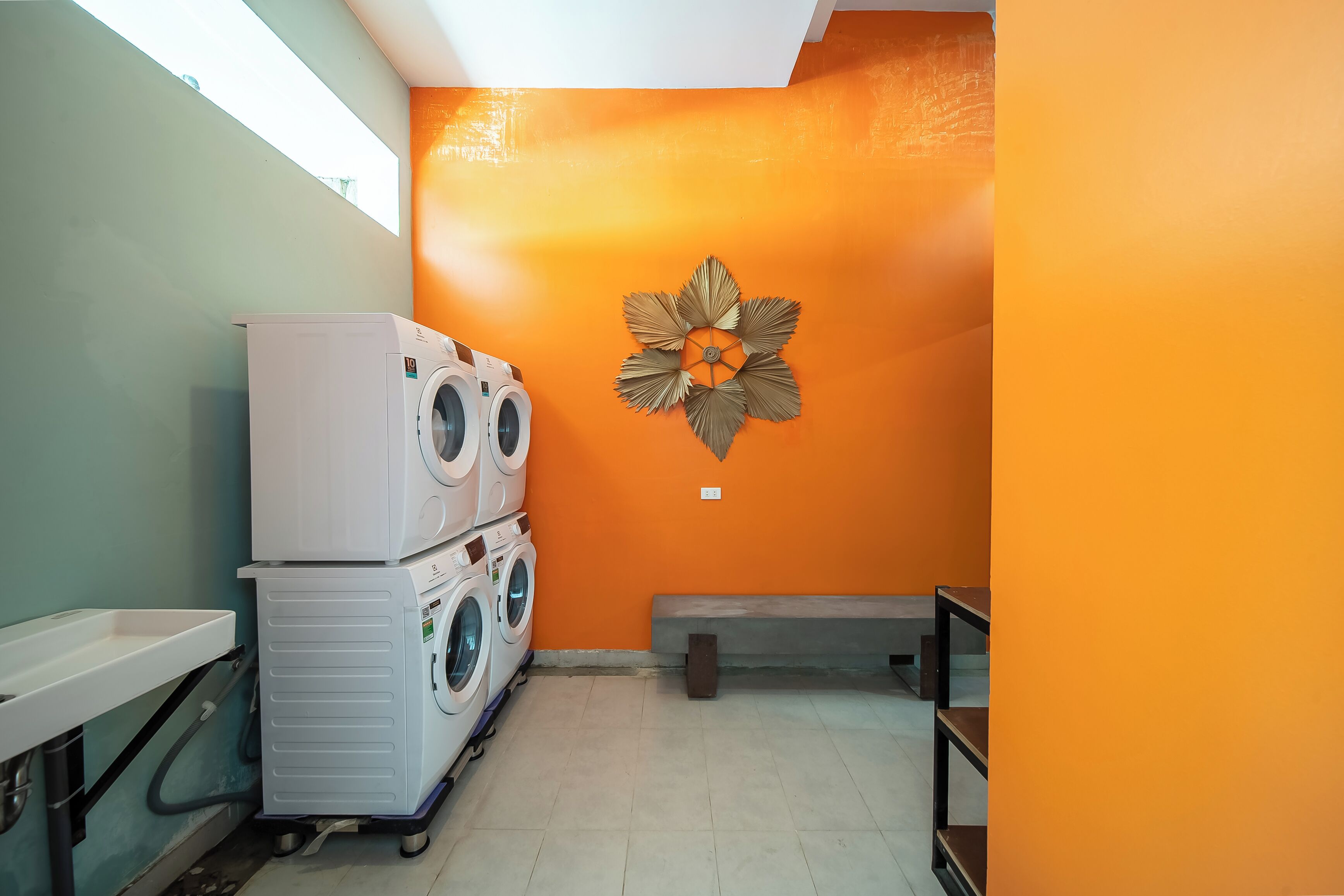 Een wasserette met gestapelde wasmachines, een bank en een decoratief wandobject.