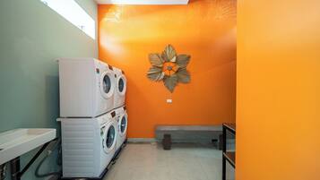 A laundry room with stacked washing machines, a bench, and a decorative wall piece.