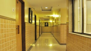 A hotel hallway with tiled walls and a shiny floor, leading to a door at the end. - Hotel Sai Suraj Palace (Rahata)