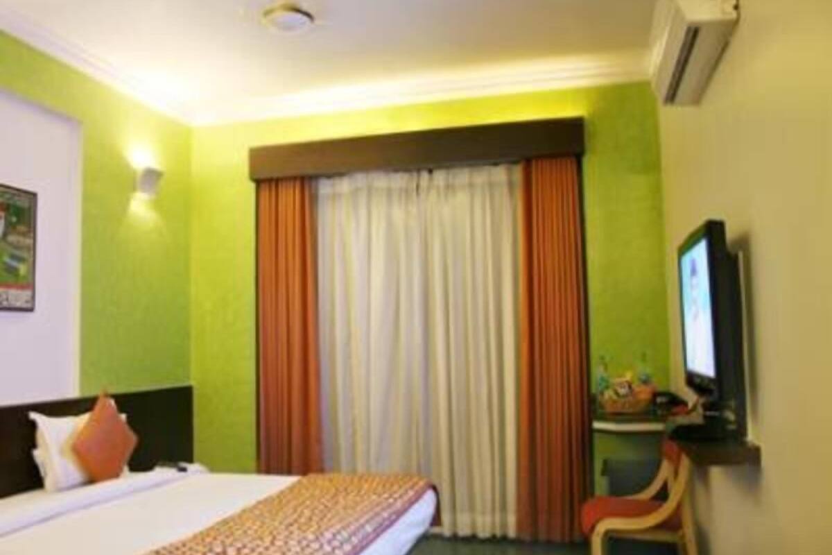 Ein Hotelzimmer mit Bett, Fernseher, Stuhl und einem Fenster mit Vorhängen.