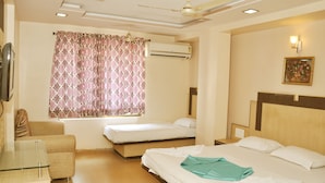 A hotel room with two single beds, a sofa, a TV, an air conditioner, and a ceiling fan. - Hotel Sai Suraj Palace (Rahata)