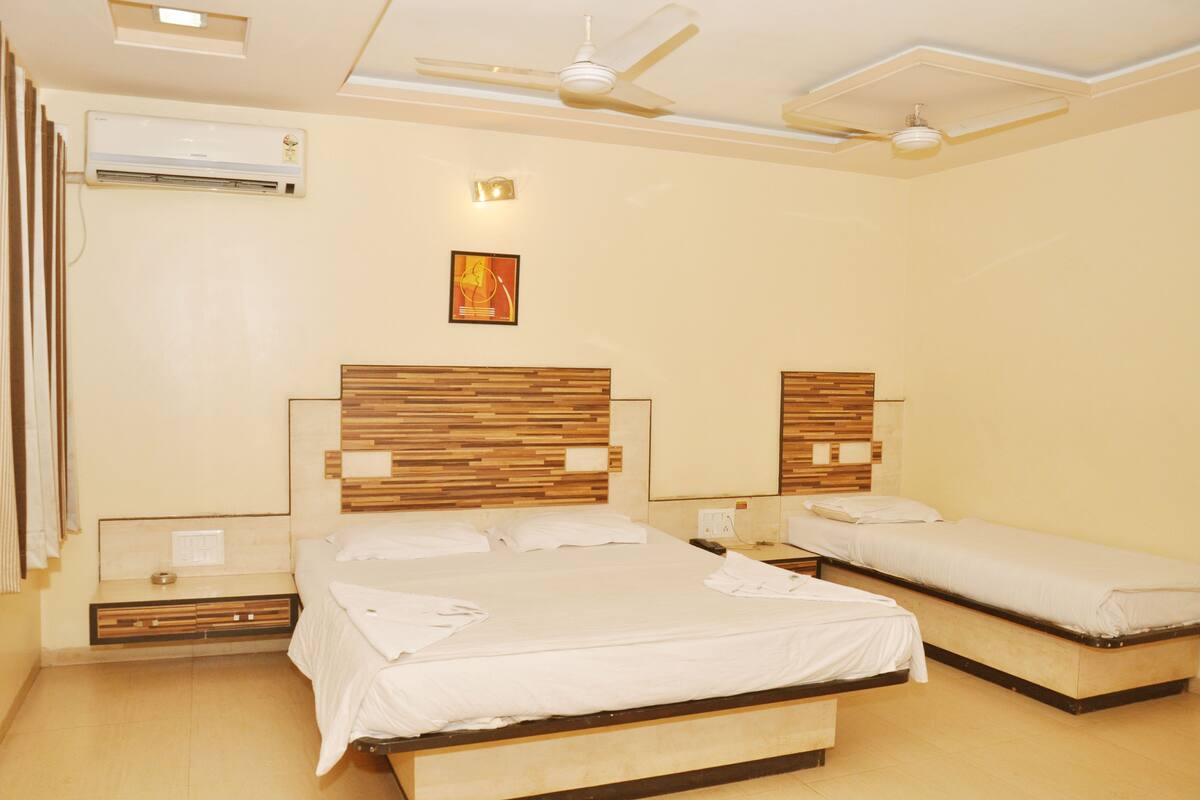 Ein Hotelzimmer mit zwei Betten, einem Deckenventilator, einer Klimaanlage und einer Wandleuchte.