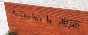 Une enseigne en bois portant l’inscription « As One Style In - 湘南 ».