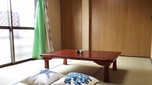Una habitación japonesa tradicional con suelo de tatami, una mesa de madera y dos cojines con diseños azules.