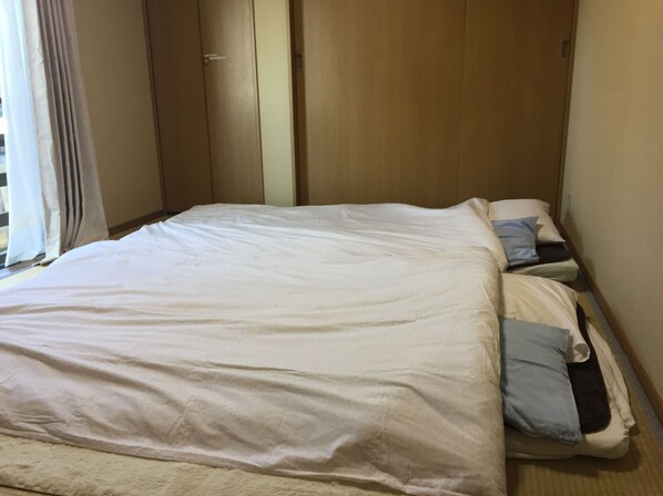 A hotel room with a large bed, a wooden wardrobe, and a window with curtains. - AS ONE Style in Shonan (Kamakura)