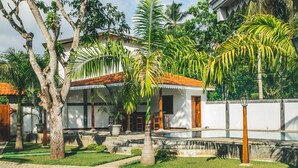 A traditional house with a tiled roof, surrounded by lush greenery and a small pool. - Sisikirana Villa (Unawatuna)