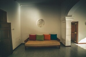 Una habitación con un sofá, un ventilador y una puerta.