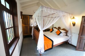 Un dormitorio con cama con dosel, una ventana con rejas y una mesita de noche con lámpara.