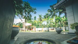 A courtyard with a central water feature, palm trees, and a building with a tiled roof. - Sisikirana Villa (Unawatuna)