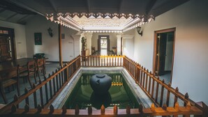 A room with a central water feature, wooden railings, and a tiled ceiling. - Sisikirana Villa (Unawatuna)