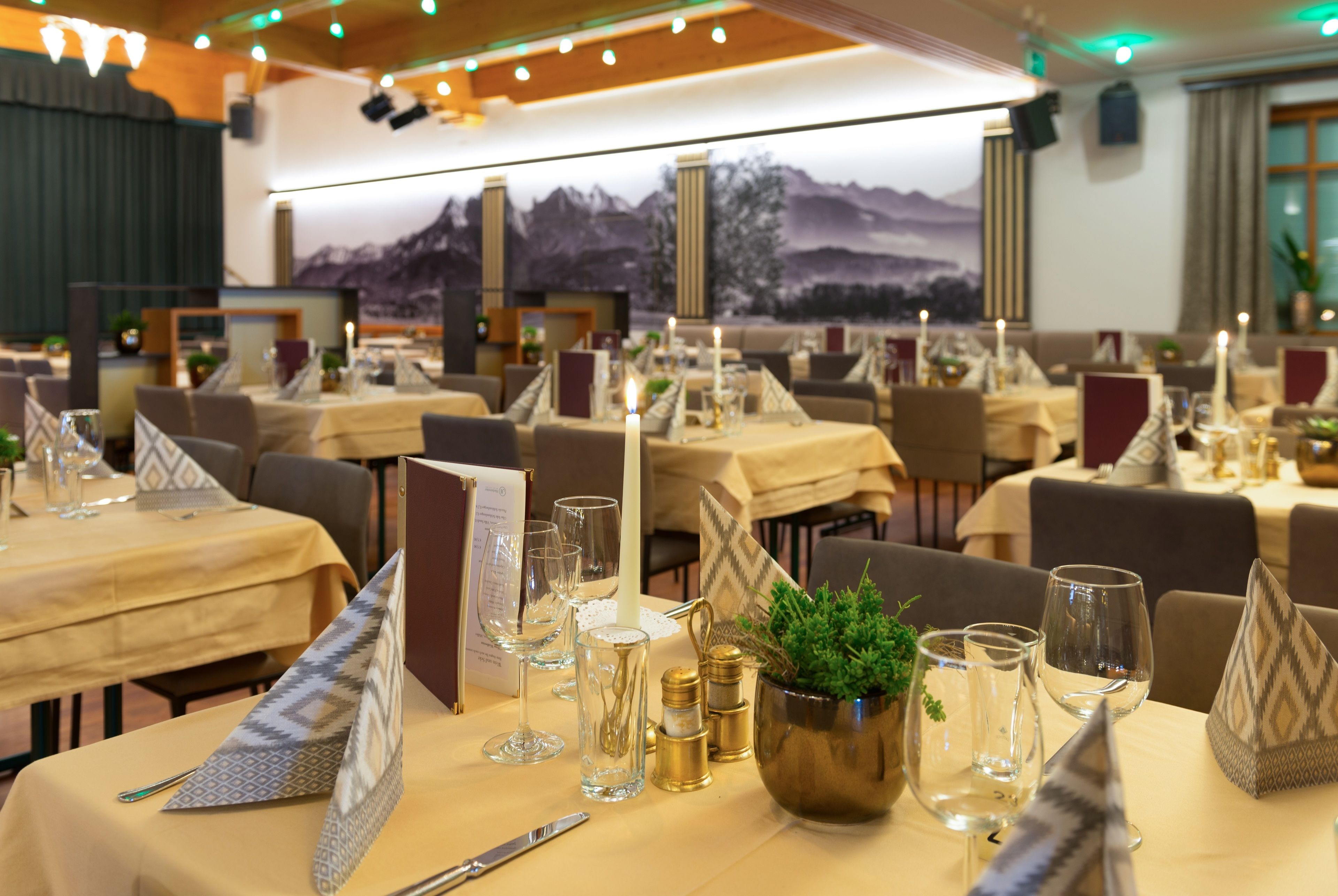 A restaurant with multiple tables set for dining, featuring clear glassware, napkins, and a decorative plant centerpiece.