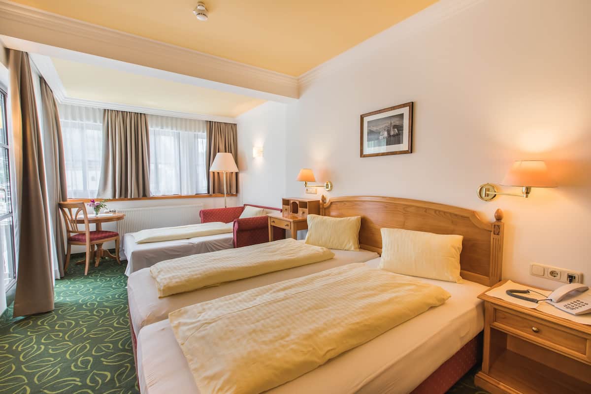 A hotel room with two beds, a desk, a chair, and a window with curtains.