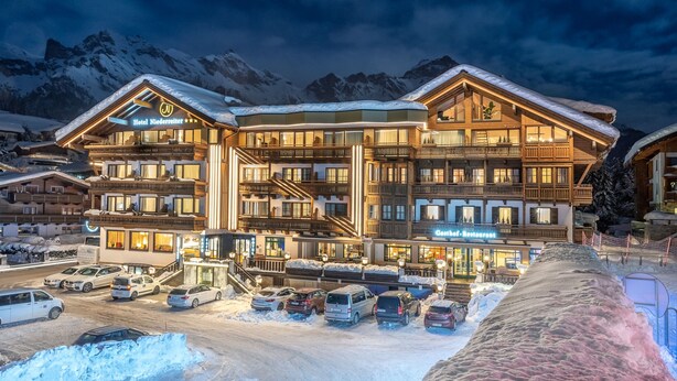 A multi-story hotel with a ski resort in the background. - Hotel Niederreiter (Maria Alm am Steinernen Meer)
