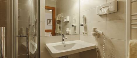 A bathroom with a glass shower enclosure, a white sink, and a towel rack.