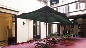 A courtyard with outdoor seating, potted plants, and a large umbrella. - Mamamia Hostel and Guesthouse (Palermo)