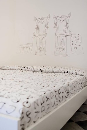 A bed with a mattress featuring a pattern of letters and numbers, and a wall with architectural sketches. - Mamamia Hostel and Guesthouse (Palermo)