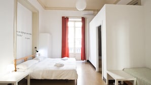 A hotel room with two beds, a desk, a wardrobe, and a window with red curtains. - Mamamia Hostel and Guesthouse (Palermo)