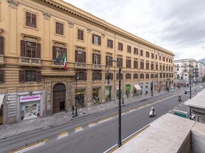 A street view with a row of buildings, shops, and a clear road. - Mamamia Hostel and Guesthouse (Palermo)