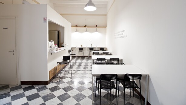 A modern kitchen with a checkered floor, white walls, and black chairs. - Mamamia Hostel and Guesthouse (Palermo)