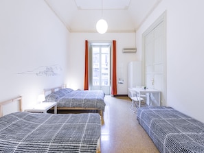 A hotel room with two single beds, a desk, a chair, and a large window with curtains. - Mamamia Hostel and Guesthouse (Palermo)