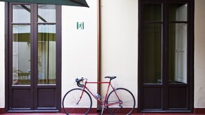 A red bicycle parked next to a door with a green emergency exit sign. - Mamamia Hostel and Guesthouse (Palermo)
