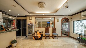 A hotel lobby with a reception desk, seating area, and a large window offering a view of the city. - Hotel Juliano (Manila)