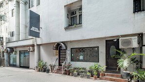 A hotel named "Hotel Juliano" with a modern facade, a staircase leading to the entrance, and multiple potted plants on the sidewalk. - Hotel Juliano (Manila)