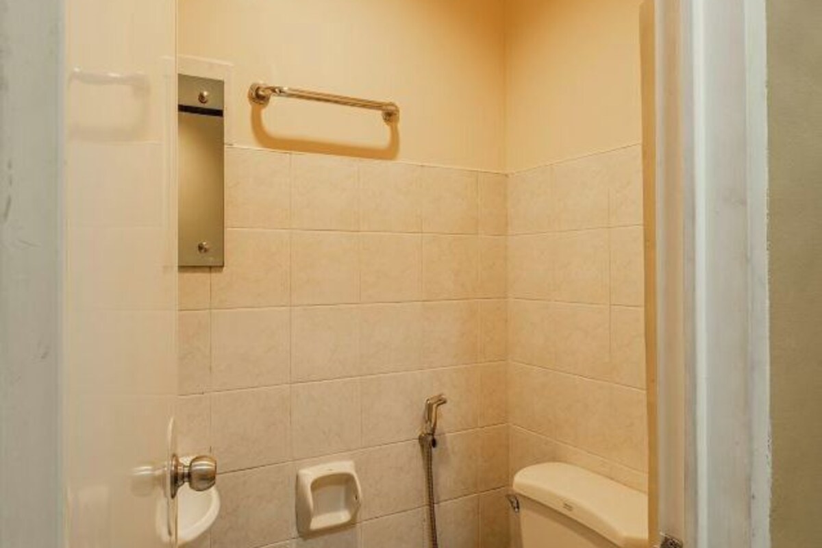 A small, tiled bathroom with a toilet, a hand dryer, and a shower area.