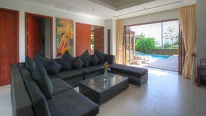 A modern living room with a sectional sofa, a glass coffee table, and a view of a swimming pool.